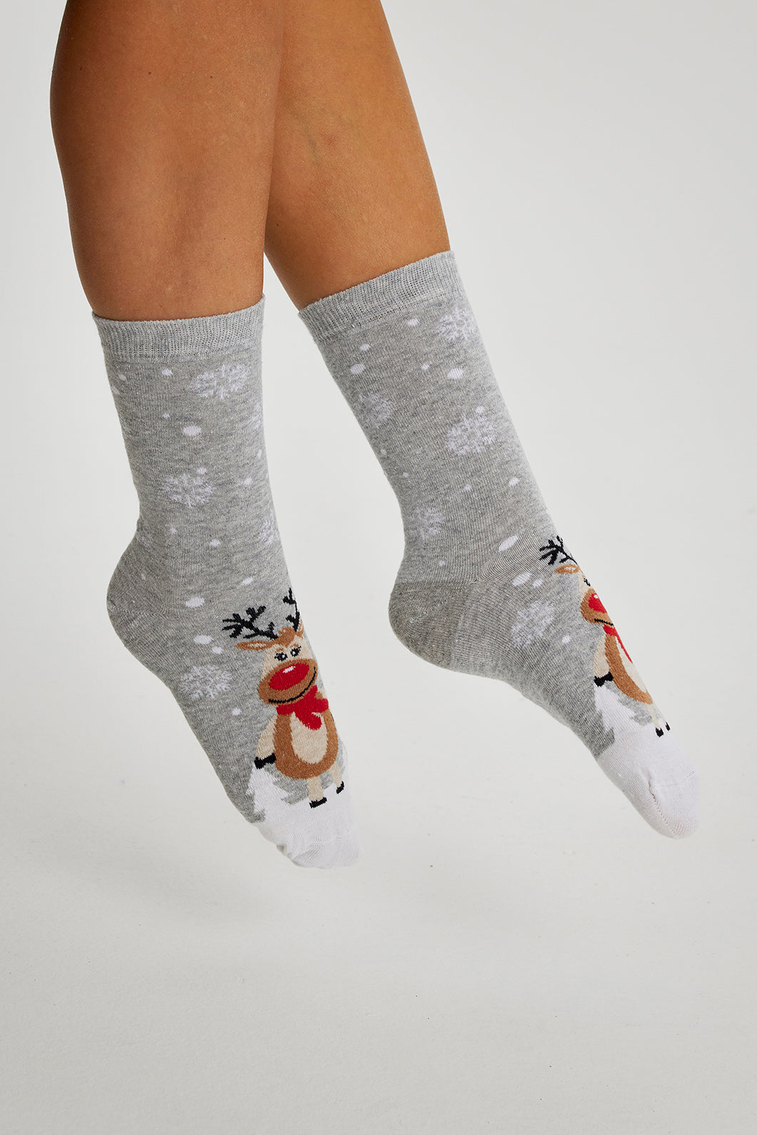 Ein Paar Beine mit grauen Weihnachtssocken mit Rudolph drauf.